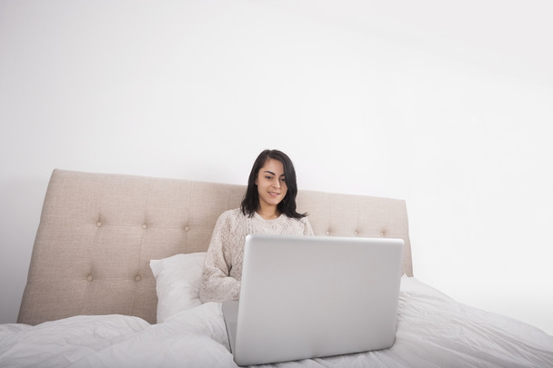 Woman using laptop on bed - Фото, зображення