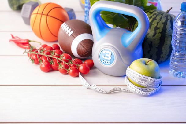 Fitness koncepció. Egészséges táplálkozás: gyümölcsök és zöldségek. Felszerelés fitnesz feladatokhoz: súlymérő gép és súlyzó fa fehér asztalra. - Fotó, kép