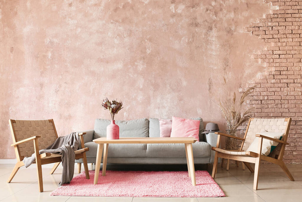 Wnętrze nowoczesnego pokoju z sofą, fotelami i drewnianym stołem w pobliżu ściany kolor - Zdjęcie, obraz
