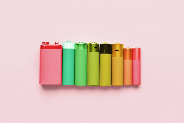 ピンクの背景にカラフルな電池のセット。エネルギー効率の概念 - 写真・画像