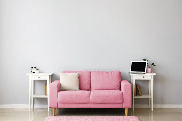 Stilvolles Interieur mit rosa Sofa und Tischen in der Nähe der Lichtwand - Foto, Bild