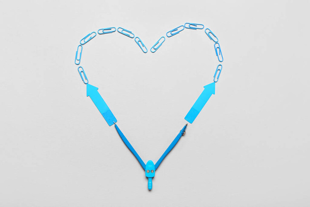 Heart made of blue paper clips, sticky notes and compasses on light background - Photo, Image