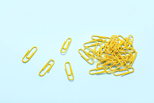 Yellow paper clips on blue background - Foto, imagen