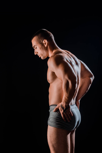 Muscular super-high level handsome man posing in studio isolated on black background - Φωτογραφία, εικόνα