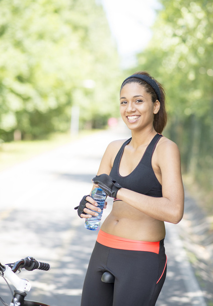Smiling woman with water bottle after exercising with bike, outd - Photo, Image