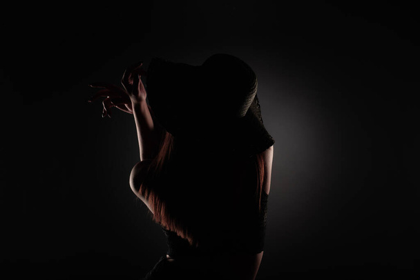 Attractive and beautiful girl is posing with her hands from the back in studio, silhouette - Foto, imagen