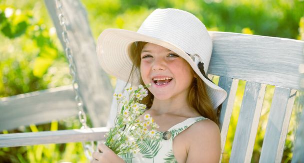 Charming blond child girl on background of flowers in summer. Pretty little child working in garden, child taking care of flowers, enjoying warm and sunny day. - Foto, afbeelding