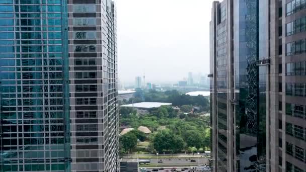 We gaan verder tussen moderne glazen wolkenkrabbers in Jakarta. Landschap uitzicht in Jakarta stad. Luchtvlucht binnen hoge gebouwen in het zakendistrict - Video