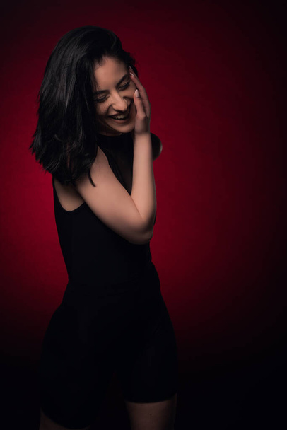 Соблазнительная девушка улыбается на съемочной площадке, будучи сексуальной в черном наряде - Фото, изображение