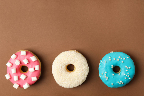 Sweet tasty glazed donuts on brown background, flat lay. Space for text - Fotoğraf, Görsel