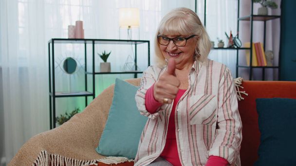 Nagymama idős nő néz kamera felemeli hüvelykujját egyetért valami pozitív otthon - Fotó, kép