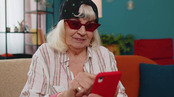 Ältere Großeltern arbeiten am Handy, verschicken Nachrichten, tätigen Online-Einkäufe zu Hause - Foto, Bild