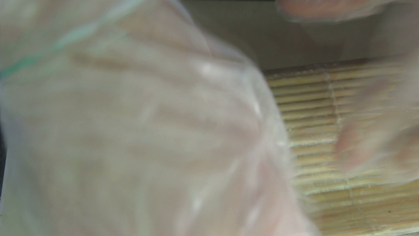 Rolling up the sushi roll with bamboo mat, close up view - Metraje, vídeo