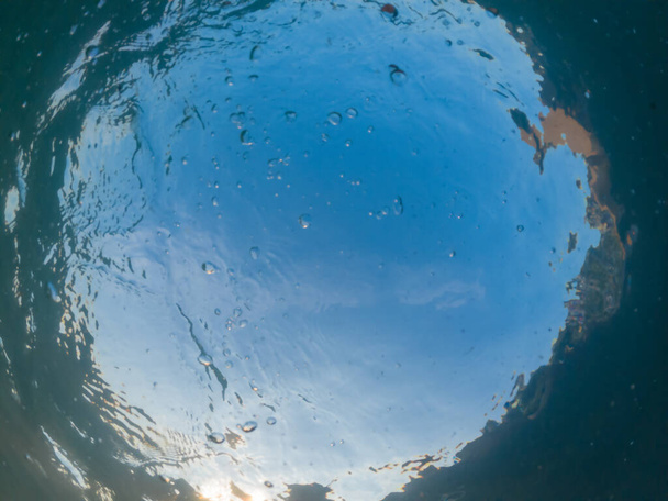 Vue du ciel bleu à travers l'épaisseur de l'eau de mer turquoise. Photo sous-marine. Vue du bas vers le haut - Photo, image