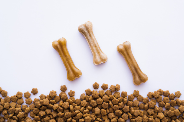 top view of bone shaped dog treats near pet food - Foto, Bild
