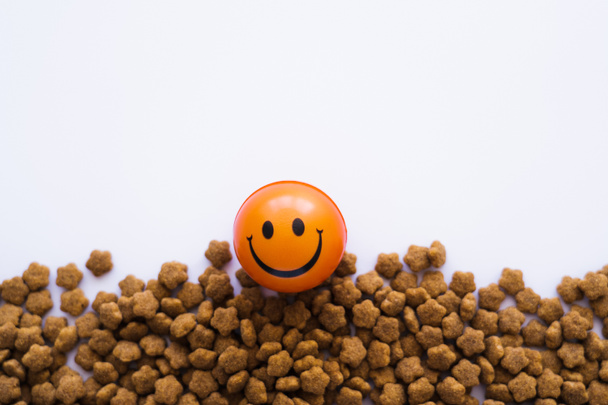 bola con emoticono sonriente cerca de alimentos para mascotas aislados en blanco - Foto, Imagen