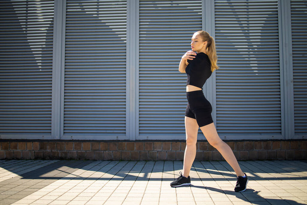Fitness runner body close up, woman doing warm-up before jogging, stretching leg muscles, Female athlete prepares legs for cardio workout, outdoor exercise in city. - 写真・画像