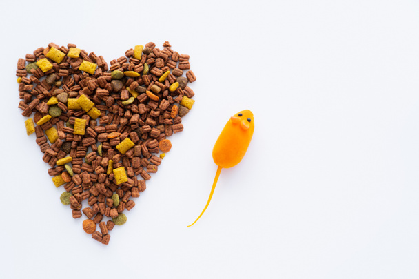 top view of dry cat food in shape of heart near near rubber toy mouse isolated on white - Fotografie, Obrázek