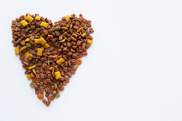 vista superior del corazón hecha de crujiente comida seca para mascotas aislada en blanco - Foto, Imagen