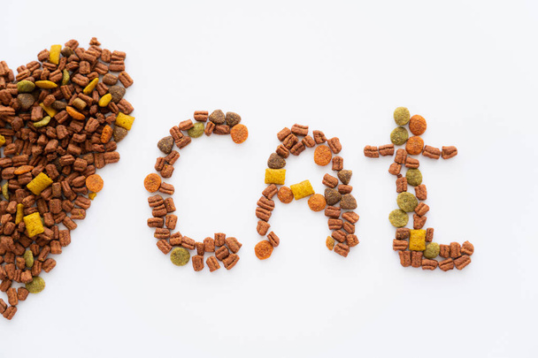 vista superior de corazón y gato palabra hecha de alimento seco para mascotas aislado en blanco - Foto, imagen