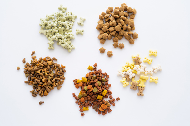 vista superior de diferentes alimentos secos e guloseimas saborosas para animais de estimação isolados em branco - Foto, Imagem