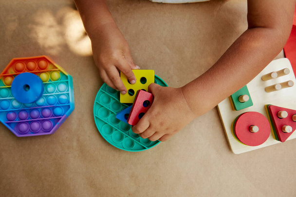 幼児は、カラフルなストレス感知おもちゃのフィジェットプッシュでそれを再生します。トレンディポップそれは良いモータースキルの開発のためのおもちゃ。虹の感覚のフィジェット。新しいトレンディーなシリコーンおもちゃと木製エコおもちゃ - 写真・画像