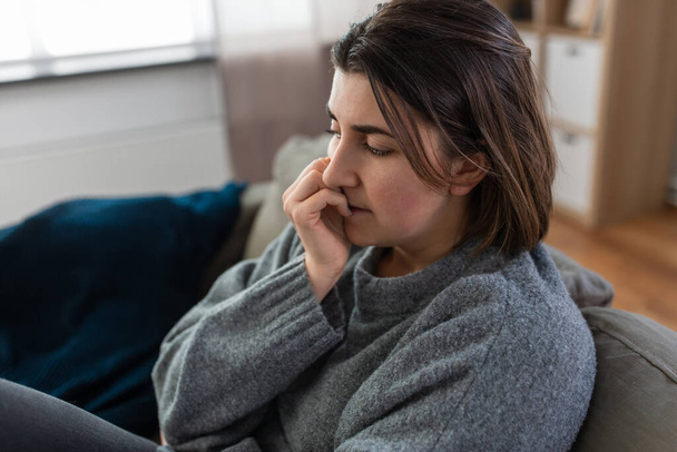 stressed woman sitting on sofa at home - Photo, Image