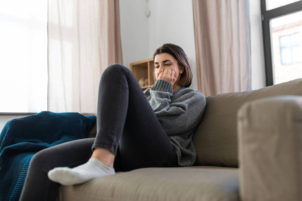 stressed woman sitting on sofa at home - Foto, afbeelding