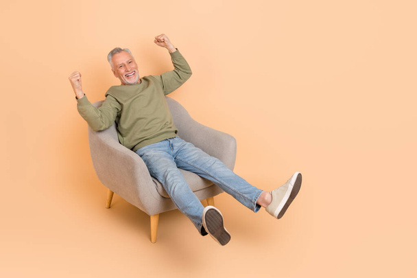 Full body photo of cool aged grey hairdo man sit yell wear pullover jeans shoes isolated on beige background - Fotografie, Obrázek