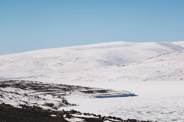 Landscape view of Frozen Cildir lake in Kars and snowy mountains with a blue sky in winter. - Fotoğraf, Görsel