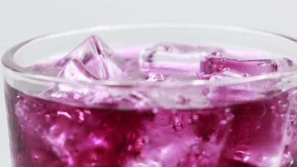 Ruotare il bicchiere di bevanda acqua frizzante uva su sfondo bianco. - Filmati, video