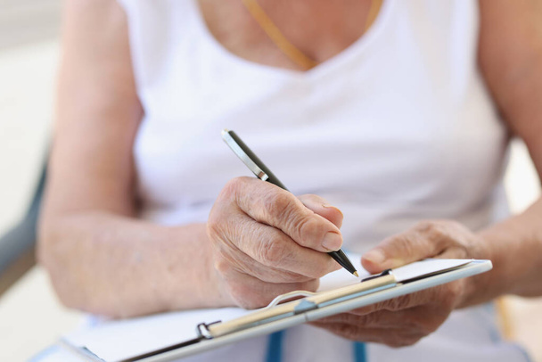 Руки пожилой женщины с листом для написания текста - Фото, изображение