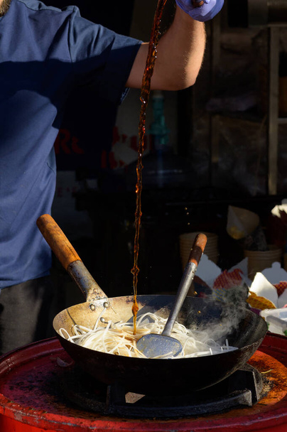Chef cooks Chinese noodle wok at street food festival - 写真・画像