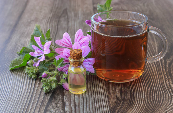 Hibiszkusz tea és hibiszkusz virágok egy üvegpohárban egy fa asztalon. Vitamintea hidegre, influenzára és hibiszkuszolajra üvegben - Fotó, kép