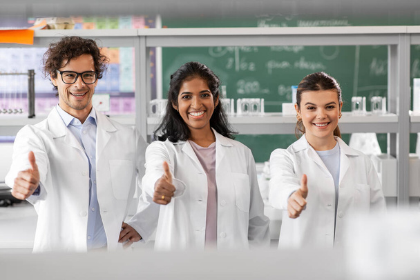 happy scientists showing thumbs up in laboratory - Foto, Bild