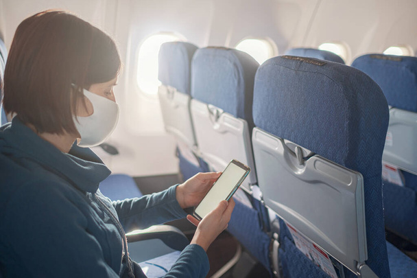 Genç ve güzel bir kadın uçuş sırasında uçağın penceresinde oturuyor. - Fotoğraf, Görsel