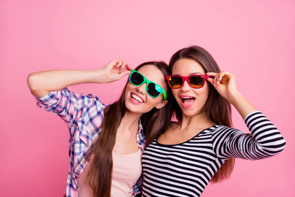 Foto de dos positivos alegres damas brazo tacto gafas buen humor aislado sobre fondo de color rosa - Foto, imagen