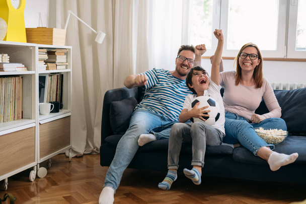 young caucasian family watching football game and cheering at home - Fotoğraf, Görsel