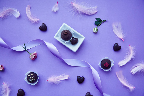 チョコレートお菓子と心。流行のピンクの羽。繊細な紫色の非常にパーイ色のパターン。誕生日、招待状、挨拶、希望のコンセプト. - 写真・画像