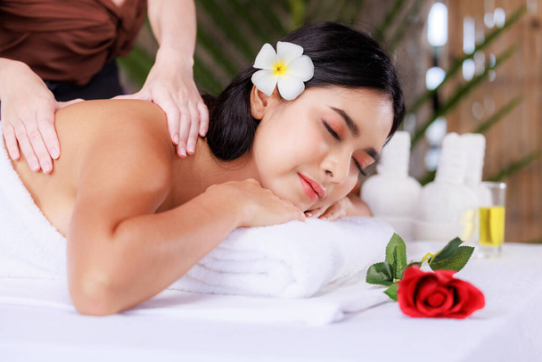 close up beautiful young asian woman lying relaxing in the spa salon massage flower red in front, health and body care concept, - Photo, Image