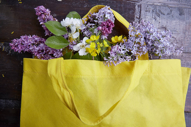 Bouquet of spring lilies, apricot blossoms, blooms in a yellow bag. Sustainable, cottage core, connecting with nature concept. - Photo, Image