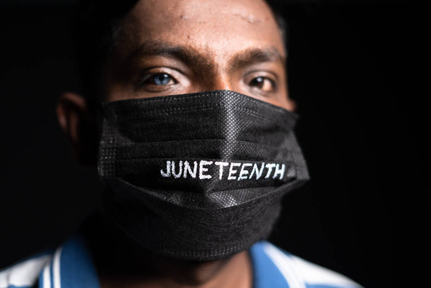 Primo piano di un uomo con juneteenth maschera viso medico guardando la fotocamera durante coronavirus covid pandemia - concetto di libertà e libertà - Foto, immagini