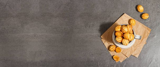 Kekse in Form von Walnüssen mit Kondensmilchcremefüllung. Leckere Shortbread-Sandwiches, modernes veganes Backen. Stein Beton Hintergrund, Banner-Format - Foto, Bild