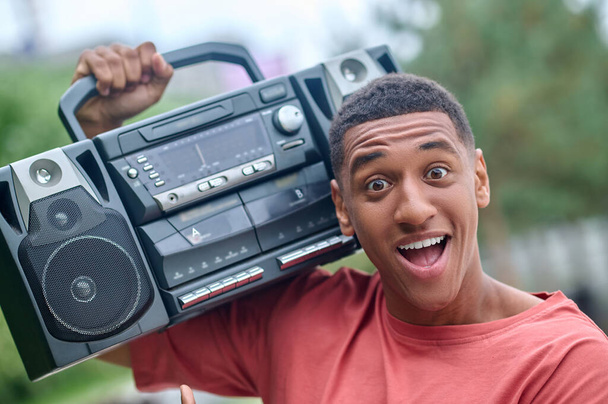 Guy with record-player on shoulder enthusiastically looking at camera - Photo, image
