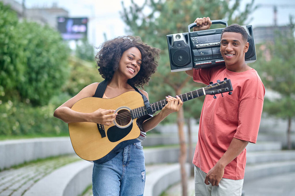 Girl with guitar guy with record-player looking at camera - Foto, Bild