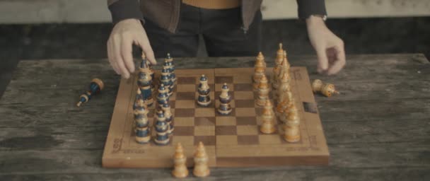 Człowiek ręce układają figury szachowe na szachownicy na drewnianym stole - Materiał filmowy, wideo
