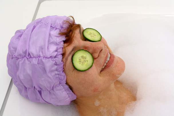 Зріла жінка у ванні з шматочками огірка на видовищі
 - Фото, зображення