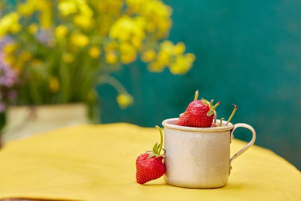  Strawberries in a metal aluminum travel mug. Green and yellow spring background. Cottagecore aesthetics concept, trendy shadows background. Copy space. High quality photo - Photo, Image