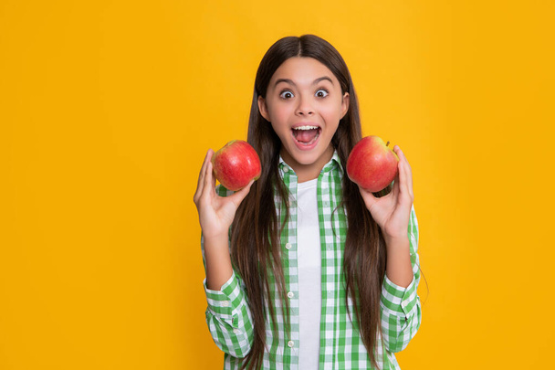 amazed child with fresh apple on yellow background - Photo, Image