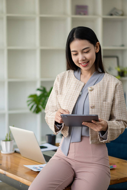 donna asiatica di successo uomo d'affari sorridente felicemente in possesso di un tablet nel quadro verticale ufficio - Foto, immagini